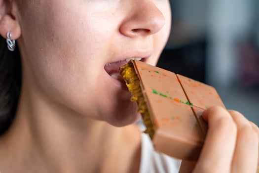 Woman eating trend Dubai chocolate with pistachio paste and kataifi dough. Confectionery handmade sweets at home in the kitchen. High quality photo