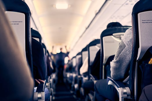 The interior of the plane with passengers sitting on the seats and a man walking down the aisle in the background. Travel concept, selective focus photo