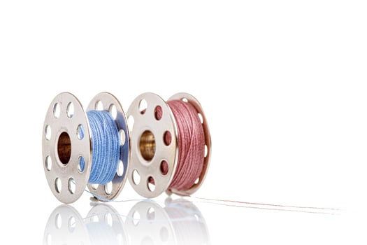 spools of blue and pink thread on a white background photo