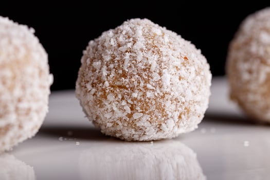 Beautiful sweets with coconut on a white plate on a black background photo