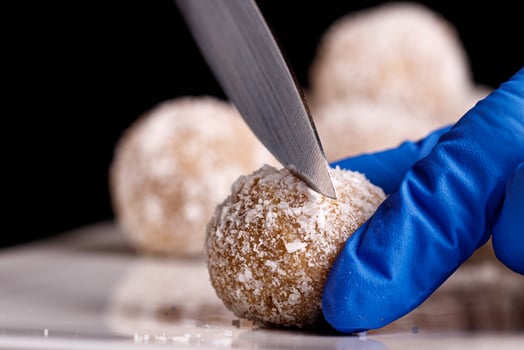 Beautiful sweets with coconut are cut with a knife on a white plate on a black background photo
