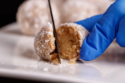 Beautiful sweets with coconut are cut with a knife on a white plate on a black background photo