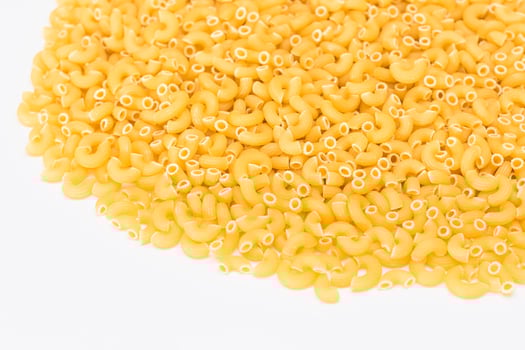 A Heap of Uncooked Chifferi Rigati Pasta on White Background. Fat and Unhealthy Food. Classic Dry Macaroni Texture. Italian Culture and Cuisine. Raw Pasta photo
