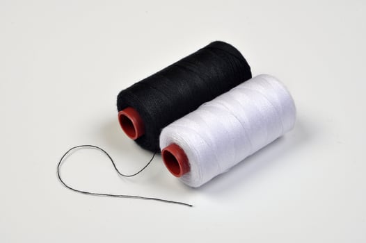 Spool of black and white sewing thread selective focus photo
