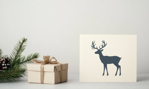 A white box with a ribbon sits next to a blue and white deer card photo