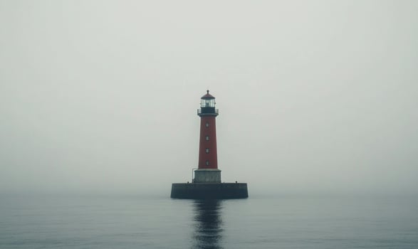 A lighthouse is standing on a rocky island in the middle of the ocean photo