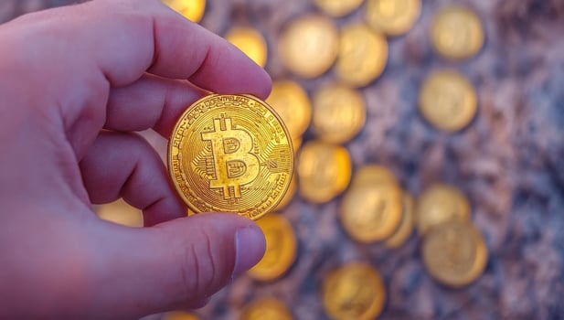 Hand holding a Bitcoin against a background of Bitcoins. Concept of cryptocurrency investment. photo