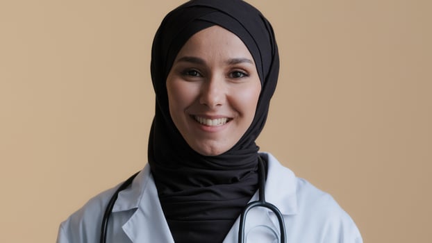 Young muslim professional woman female doctor physician in hijab white medical uniform consulting remote patient looking at camera webcam virtual chat providing distant medical services teach photo