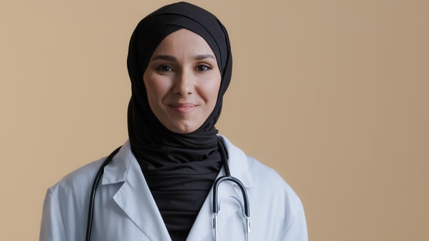 Portrait happy smiling muslim arab woman islamic doctor physician in hijab wear white medical coat looking at camera posing positive young female practitioner professional therapist standing indoors photo