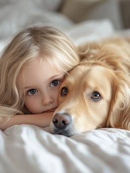 A little girl and a golden retriever laying on a bed photo