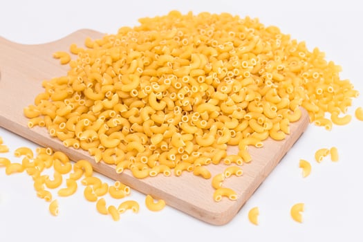 A Heap of Uncooked Chifferi Rigati Pasta on Wooden Kitchen Board. Fat and Unhealthy Food. Classic Dry Macaroni. Italian Culture and Cuisine. Raw Pasta photo