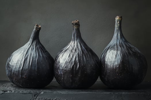A pyramid of fresh dark figs arranged on a textured surface in a low light setting photo