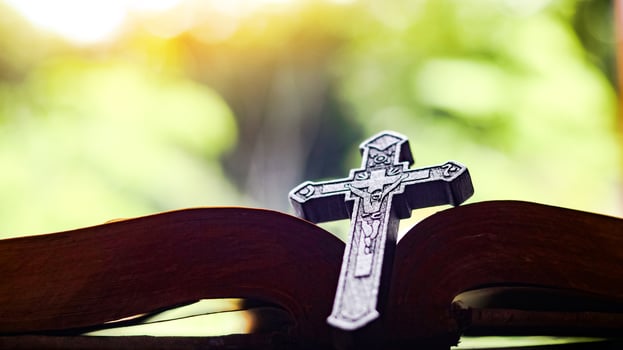 Dark brown wooden cross on an old open book symbolizing the spread of Jesus Christs love among Christians reflecting faith devotion and the importance of Christian teachings. photo