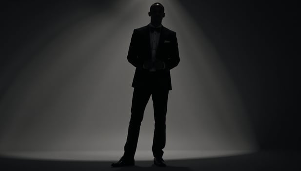 AfricanAmerican man silhouetted against a light background while wearing a tuxedo photo