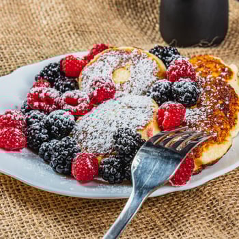 Cottage cheese pancakes with fresh raspberries, blackberries and powdered sugar photo