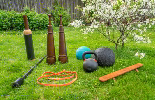 fitness equipment on green lawn in springtime scenery, backyard gym concept photo