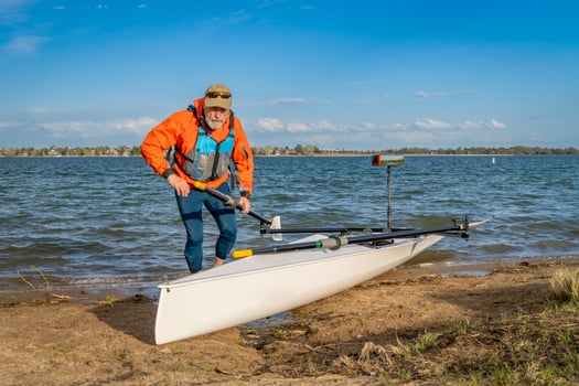Senior male rower with his rowing shell on a beach of Boyd Lake in northern Colorado, early spring scenery photo