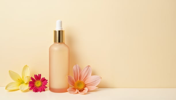 A bottle of cosmetic oil and flowers on a yellow background photo