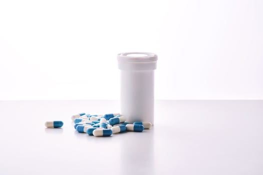 Bottle with white and blue capsules on a white background. photo