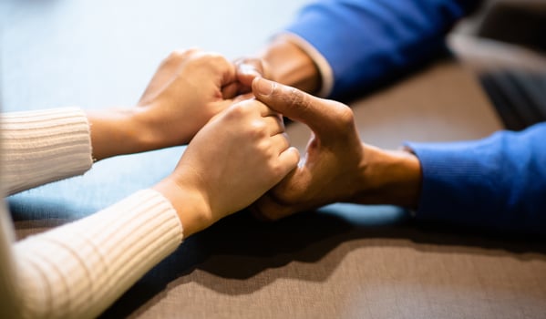 Close up of young multiethnic couple warmly holding hands sitting at table in coffee shop, copyspace photo