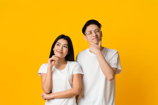Planning future together. Young asian couple day dreaming on yellow studio background photo