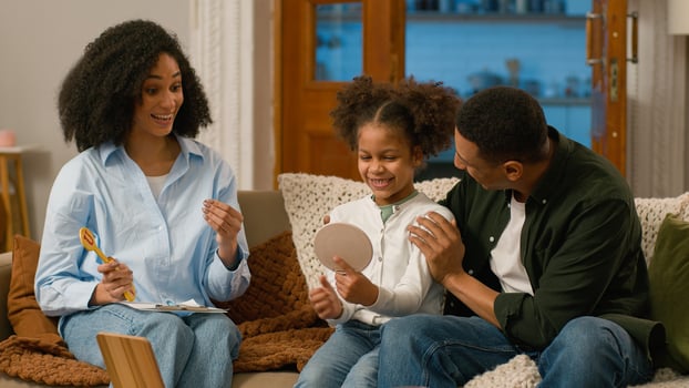 African American speech therapist mother father parents family child daughter learning talk pronounce word letter articulation support speak language praise achievement teamwork progress sound proud photo