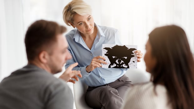 Family Therapy. Psychologist Testing Couple Showing Inkblot Picture During Psychotherapy Session Sitting In Office. Selective Focus photo