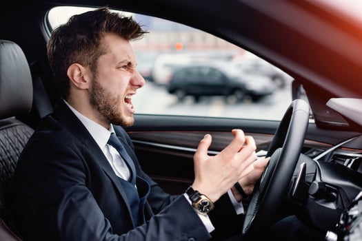Angry Driver Concept. Aggressive mad man in suit driving car in urban city, angrily gesturing photo