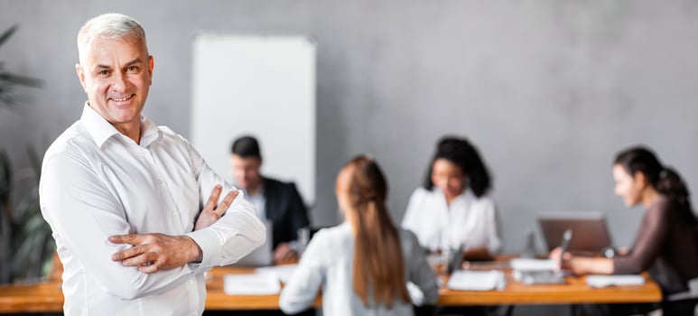 Business Leadership. Smiling Businessman Standing Crossing Hands In Front Of Employees Team In Modern Office. Empty Space photo