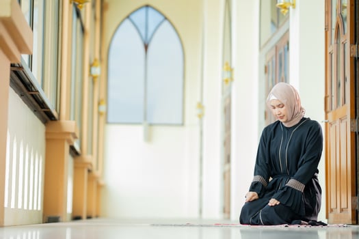 The image of an Asian Muslim woman in the Islamic religion in hijab in cream color. She was praying in a beautiful mosque out of respect for God. photo