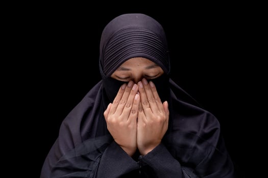 Portrait Asian Muslim woman wearing black hijab is praying for prayer with faith and determination. on black background. photo
