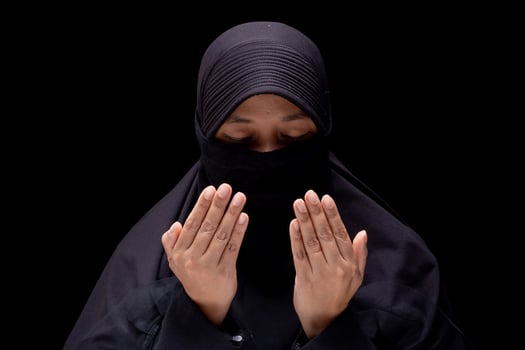 Portrait Asian Muslim woman wearing black hijab is praying for prayer with faith and determination. on black background. photo
