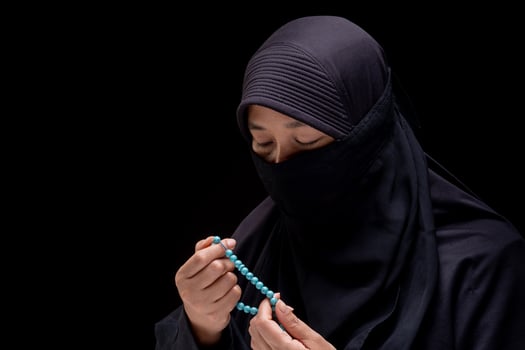 Portrait Asian Muslim woman wearing black hijab is praying for prayer with faith and determination. on black background. photo