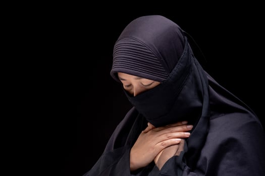 Portrait Asian Muslim woman wearing black hijab is praying for prayer with faith and determination. on black background. photo
