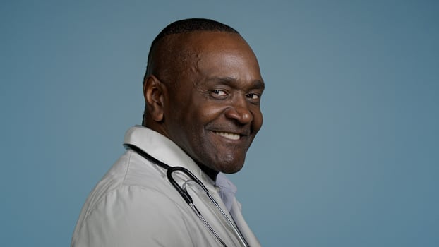 African american man doctor male professional physician medical worker healthcare therapist surgeon employee standing with back turning around looking camera smiling posing in studio blue background photo