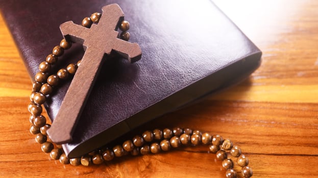 Dark brown wooden cross on a dark brown book symbolizing the spread of Jesus Christs love among Christians reflecting faith devotion and the importance of Christian teachings. photo