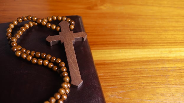 Dark brown wooden cross on a dark brown book symbolizing the spread of Jesus Christs love among Christians reflecting faith devotion and the importance of Christian teachings. photo