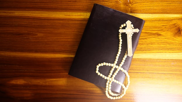 Brown wooden cross on a brown book symbolizing the spread of Jesus Christs love among Christians reflecting faith devotion and the importance of Christian teachings. photo