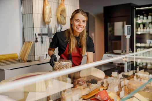 A Cheese Shop Employee Passionately Serving Customers with an Array of Fresh Products photo