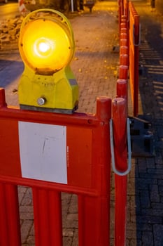 Flashing yellow light on red and white construction barrier at night photo