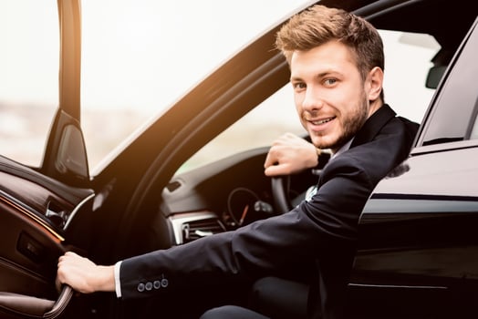 Confident Chauffeur. Guy in suit sitting in driver's seat, getting in his car at downtown area, closing the door photo