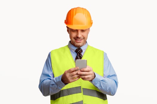 Construction Worker Using Smartphone Application Standing On White Studio Background. Mobile App Concept photo