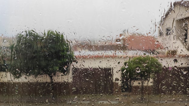 Rain-covered window view of a suburban neighborhood with blurred background photo