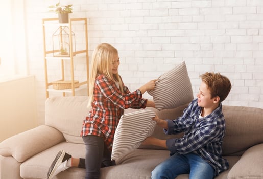 Happy Brother And Sister Having Pillow Fight Laughing And Playing Together On Couch At Home. Siblings Friendship photo