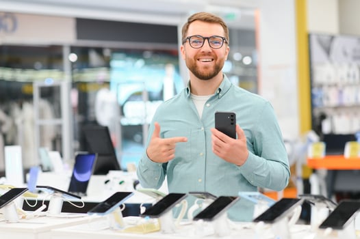 happy young man choosing a new mobile in a tech store photo