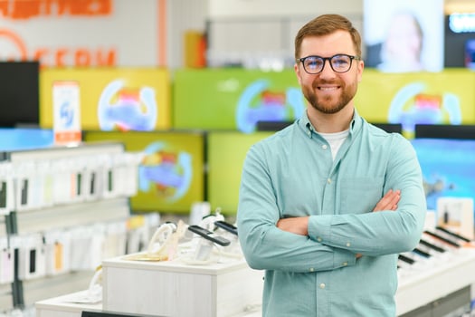 A man stands near mobile phones in an electronics store. photo