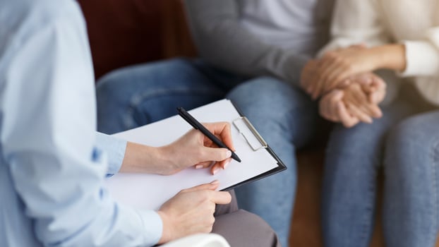 Family Psychotherapy. Marital Therapist Taking Notes Talking With Couple Sitting In Office. Cropped, Selective Focus photo