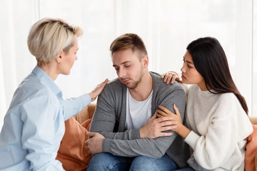 Fighting Addiction. Wife And Family Psychologist Comforting And Supporting Depressed Addicted Husband At Psychotherapy Session Indoor photo