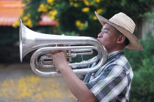 Asian man is playing the euphonium. Concept, love music, hobby, recreation activity. Relax time. Lifestyle. Music can develop mental health. Mouthpiece musical instrument. Rehearsal music. photo