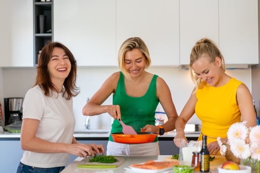 Cheerful female friends preparing lunch together at kitchen counter photo